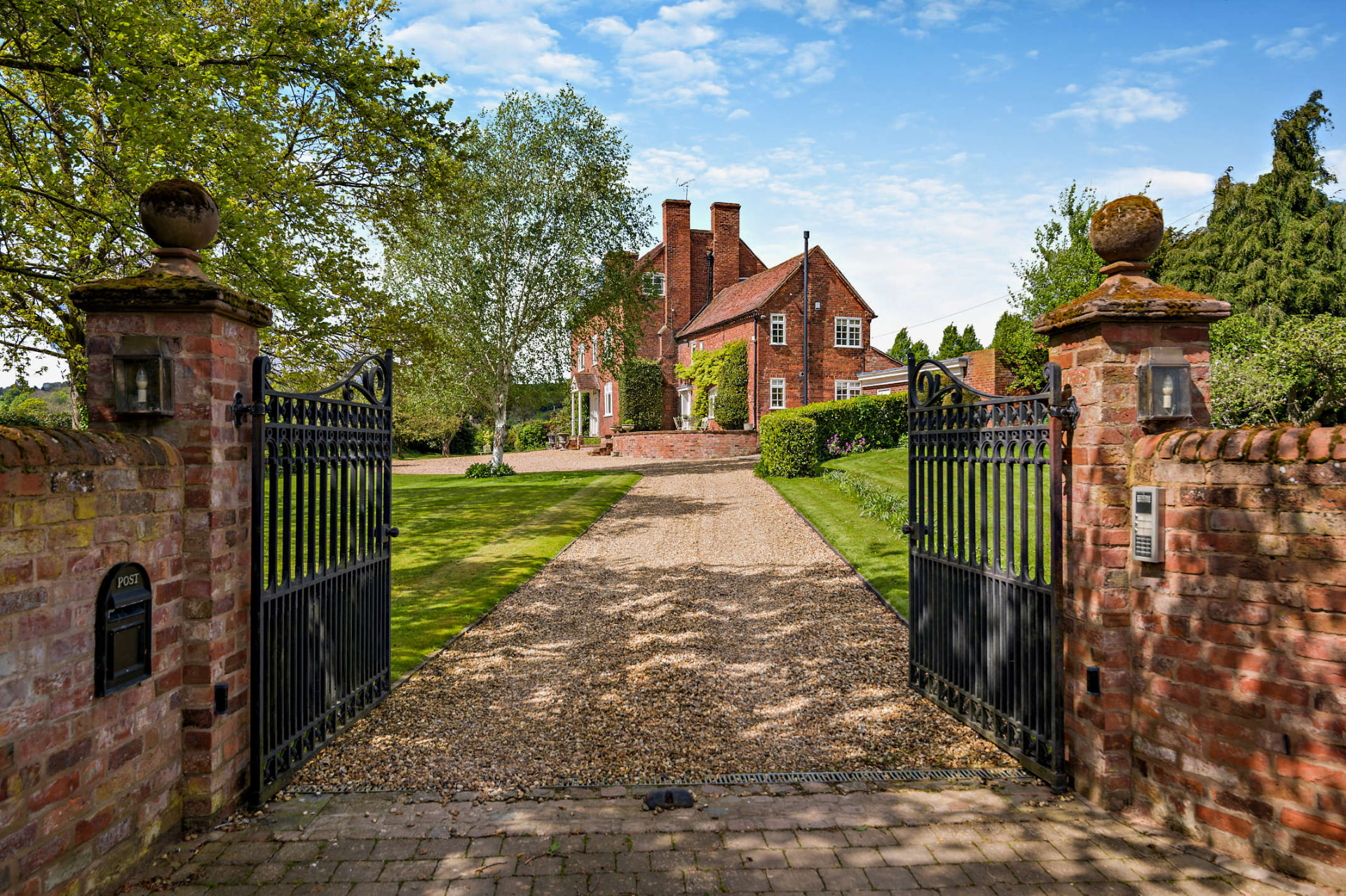 Open gates leading up a gravel driveway to a country house